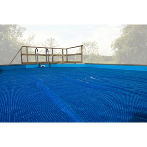 Bâche thermique bleue sur piscine en bois massif, couverture solaire pour chauffer la piscine.