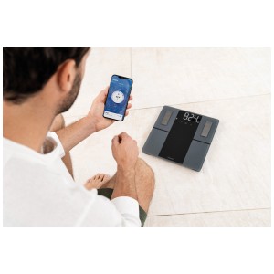 Pèse-personne impédancemètre Beurer BF 500 Super Black Edition avec connexion à l'application et personne sur la balance.
