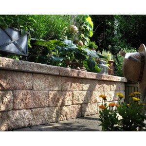 Demi-élément de mur en pierre concassée couleur grès, partie d'un mur de jardin avec des plantes.