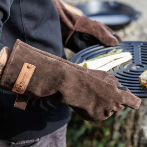 Gants de barbecue Petromax XL marron foncé en cuir velours lors d'un barbecue.