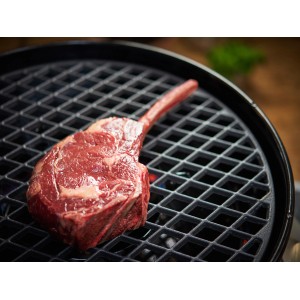 Grille en fonte Outdoorchef Diamond 420 avec steak sur le gril. Ustensile de grill pour des rayures parfaites.