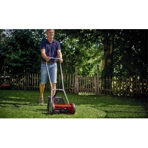 Homme tondant la pelouse avec la tondeuse à main rouge Einhell GC-HM 300 dans le jardin.