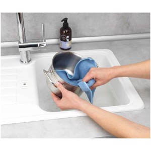 Wenko Panno spugna Miko, blu/grigio, set da 2, mentre pulisce una pentola nel lavandino.