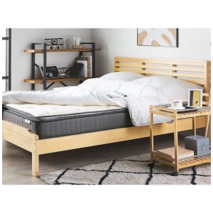 Matelas mousse à mémoire de forme Beliani Charm, 180x200 cm, blanc, sur un lit en bois avec du linge de lit blanc.