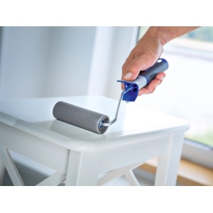 Rullo per pittura in schiuma grigia LUX PRO (5 cm x 11 cm) mentre dipinge un tavolo.