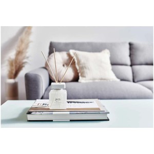 Ipuro Raumduft Essentials White Lily 200ml mit Duftstäbchen auf einem Tisch vor einem Sofa.