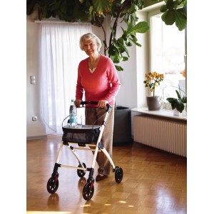 Rollator d'intérieur Ridder blanc avec plateau et panier, utilisé par une dame âgée dans un salon.