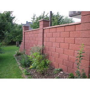 Mur de jardin brun en demi-pierres avec une surface structurée comme limite de propriété.