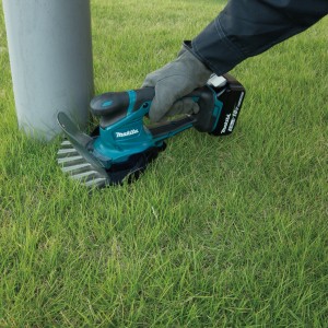 Cisailles à gazon et à arbustes sans fil Makita DUM604ZX en utilisation pour couper l'herbe.