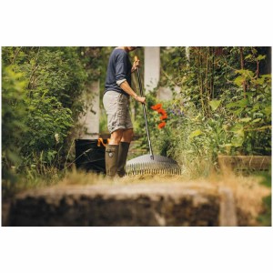 Scène de jardin avec le sac de jardin Fiskars Solid PopUp et une personne ratissant les feuilles.