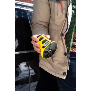 Grattoir à glace électrique jaune Kärcher EDI 4 en main devant une voiture. Aide pratique pour l'hiver.