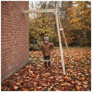 Altalena in legno Exit Toys Silvi Wall con bambino in giardino. Altalena in legno di cipresso a parete.