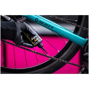 Application de l'huile pour chaîne Muc-Off Dry Lube sur une chaîne de vélo pour un entretien optimal.