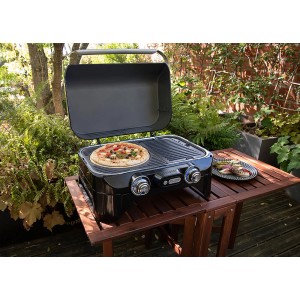 Pierre à pizza Campingaz sur barbecue : Cuisson de pizza avec ustensiles de barbecue dans le jardin.