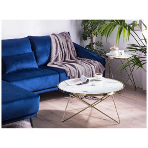 Tavolino rotondo Meridian con piano in marmo e struttura dorata davanti a un divano blu.