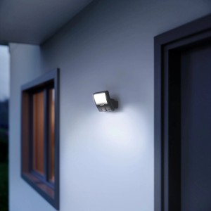 Faretto da esterno a LED Steinel XLED Curved S illuminato con sensore di movimento su parete di casa.