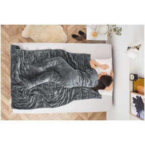 Femme sous une couverture de relaxation anthracite (135x200 cm, 6 kg) sur un lit.