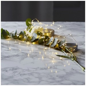 Catena luminosa LED Dew Drop argento con 40 LED bianco caldo su decorazione da tavolo.