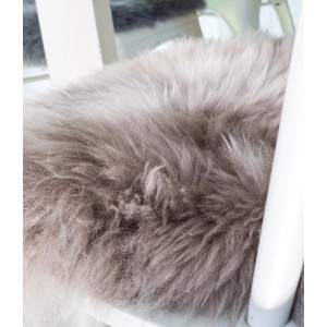 Coussin d'assise rond en peau de mouton taupe (Ø 34 cm) sur une chaise.