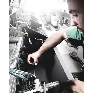 Un homme travaille sur une machine avec un tournevis Wera du set Kraftform Micro 12 pièces.