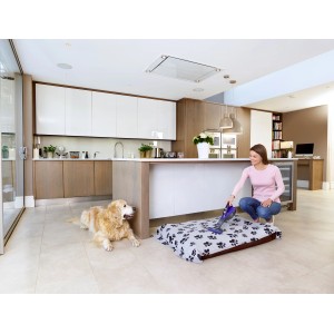 Femme aspire le panier pour animaux avec l'aspirateur à main sans fil Black+Decker Pet DVA325JP7, chien à côté.