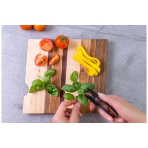 Mini-ciseaux à herbes Véritable coupant du basilic sur une planche à découper en bois avec des tomates et des poivrons.