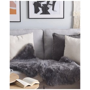 Dunkelgrauer Schaffell-Teppich Uluru Langhaar (100-110cm) auf einem Sofa. Gemütliche Wohnatmosphäre.