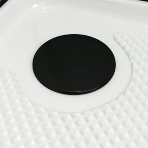 Gros plan : Bonde d'évacuation noire de la cabine de douche complète Aurlane sur receveur blanc.