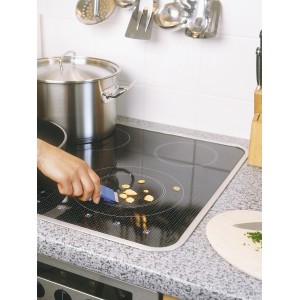 Grattoir universel LUX en utilisation pour nettoyer des résidus alimentaires sur une plaque vitrocéramique.