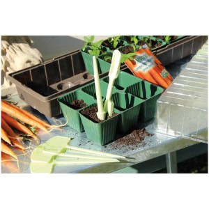 Set de repiquage Videx vert clair, 2 pièces : plantoir et fourchette dans des plateaux de semis avec terre.