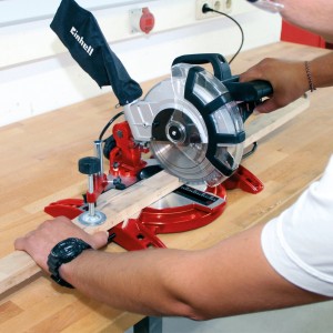 Scie à onglet Einhell TC-MS 2112 en utilisation, coupant du bois sur un établi.