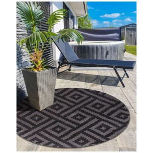 Runder Beliani Outdoor-Teppich Ajmer in Schwarz/Grau mit geometrischem Muster auf einer Terrasse. Ideal für Balkon & Garten.