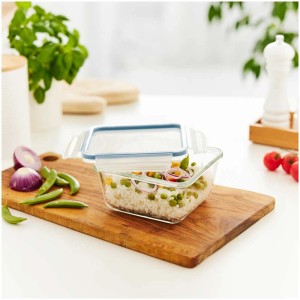 Contenitore frigo in vetro Rotho Clic&Lock (0,75 l) con riso e verdure su tagliere di legno.