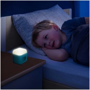 Luce notturna Reer SleepLight 2in1 celeste accanto a bambino addormentato.