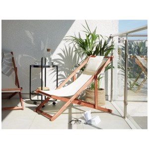 Lettino prendisole Beliani Avellino in legno acacia con rivestimento bianco crema su balcone.