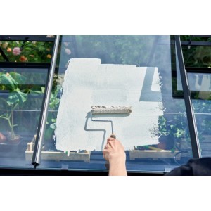 Application de la pâte d'ombrage Juliana sur une serre avec un rouleau. Protection solaire pour les plantes.