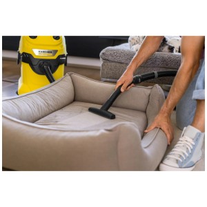 Suceur pour meubles Kärcher pour poils d'animaux utilisé sur un lit pour chien, avec un aspirateur Kärcher jaune en arrière-plan.