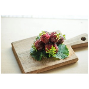 Fragole Nerina rosso scuro su tagliere di legno.