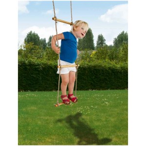Enfant grimpant à une échelle de corde avec des barreaux en bois dans le jardin. Balançoires et toboggans pour enfants.