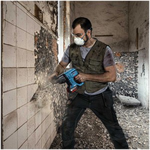 Uomo al lavoro con trapano a percussione a batteria Bosch GBH 18V-21 durante la demolizione. Set avvitatore a batteria.