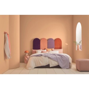 Chambre avec murs peints en Alpina Pantone Peach Fuzz orange pastel. Lit, tête de lit colorée, peinture murale mate.