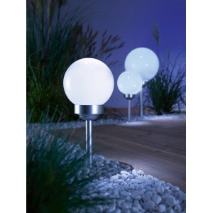 Foto di tre lampade solari a sfera Bojano bianche con picchetto da terra in giardino.
