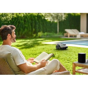 Homme lisant pendant que le robot tondeuse Mammotion Yuka Mini tond la pelouse.