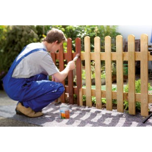 Homme peignant une clôture sur une toile de protection LUX 1x10m. Protection contre la peinture et la saleté lors du bricolage.
