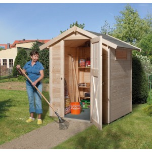 Casetta da giardino in legno OBI Outdoor Living Compact con tetto a due falde, 152x171 cm, naturale, con porta aperta e donna con rastrello.