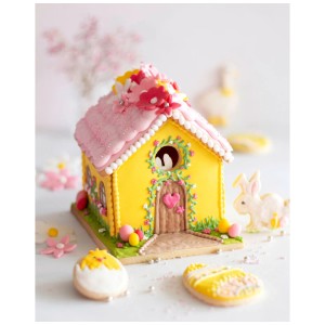 Dekoratives, gelbes Lebkuchenhaus mit rosa Dach und Blumen, gebacken mit 3-tlg. Ausstecher-Set.