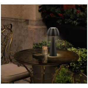 Lampada da tavolo a LED ricaricabile Schönenberger Sulis nera, luce bianca calda, su un tavolo all'aperto.