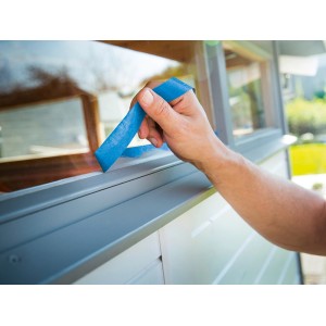 Anwendung von blauem LUX Flachkrepp Exact Line Outdoor Klebeband auf einem Fensterrahmen.
