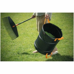 Sac de jardin Fiskars Solid PopUp 172 l avec râteau à feuilles en utilisation au jardin.