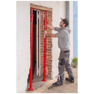 Un uomo regola un puntello universale Pro-bau-tec rosso (1,65-3 m) nella muratura.